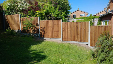 New fence panels around a back garden with houses beyond