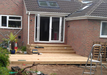 Timber decking and steps at the back of a brick extension