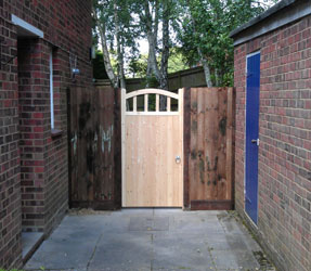 An arched top timber side gate between two brick walls