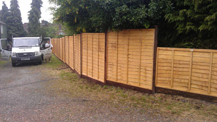 Panels on concrete posts behind freshly dug borders