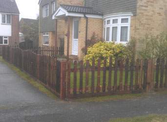 A stained picket fence around a front garden