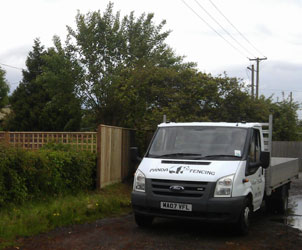 A white Panda Fencing pickup van parked by a hedge at a job